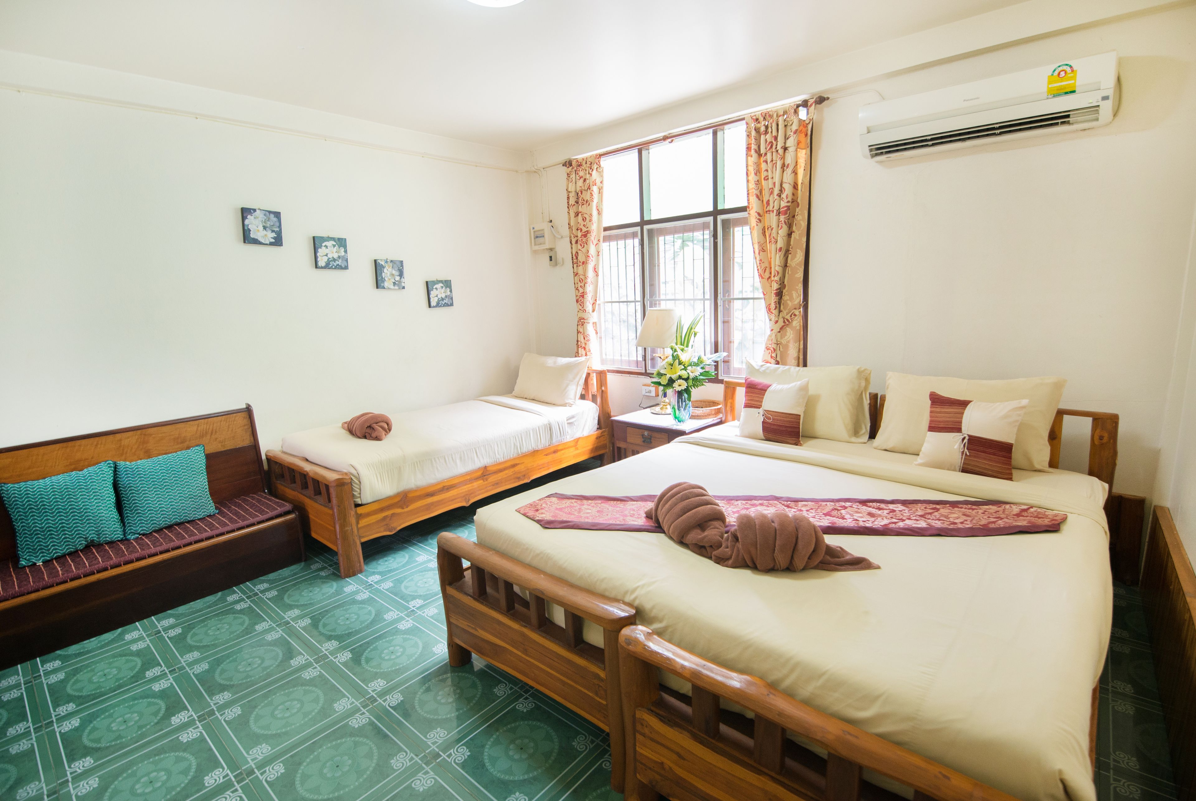A room with two single beds, a sofa, and a small table with a lamp.