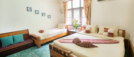 A room with two single beds, a sofa, and a small table with a lamp.