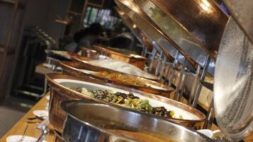 A buffet line with various dishes in metal serving trays.
