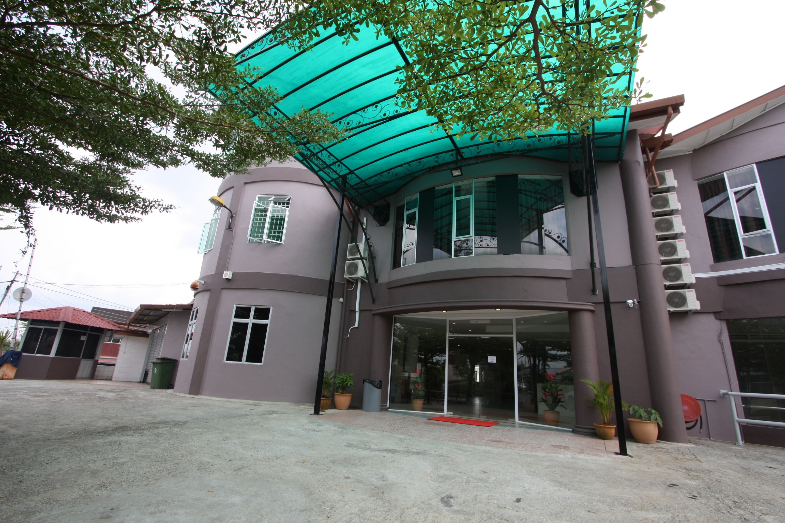 A building with a curved facade, large windows, and a covered entrance area with potted plants.