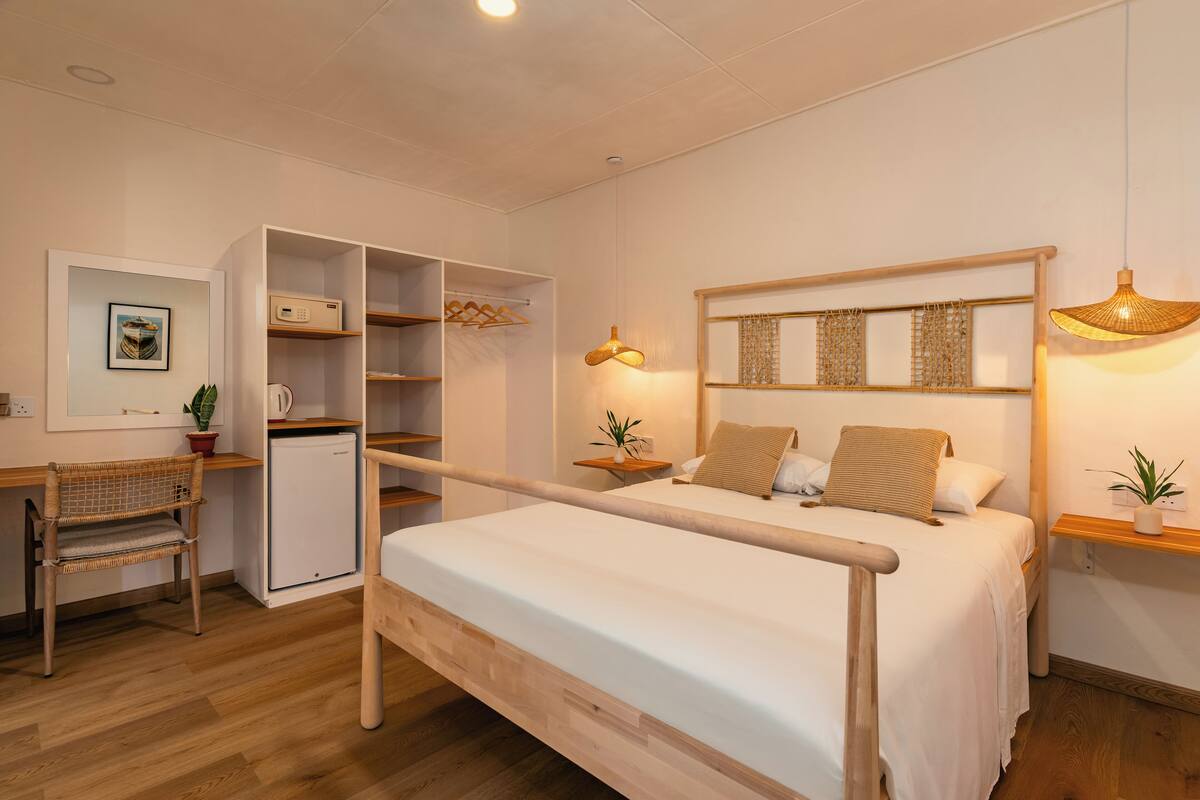 Ein Schlafzimmer mit Bett, Nachttischen, einem Kleiderschrank, einem Schreibtisch und einem kleinen Kühlschrank.