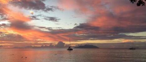 A sunset over a calm sea with boats.