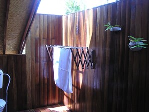 Une pièce en bois avec un portant à vêtements suspendu et une petite plante.