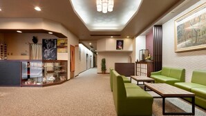 A hotel lobby with a reception desk, green seating area, and a large painting on the wall. - Hotel Mimatsu (Nara)