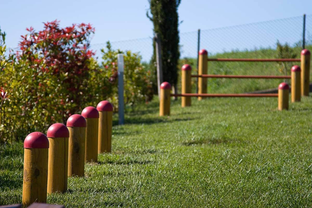 A grassy area with yellow bollards and a red gate.