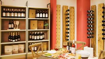 Zona pranzo con tavolo di legno apparecchiata per un pasto, circondata da scaffali e portabottiglie per vino.