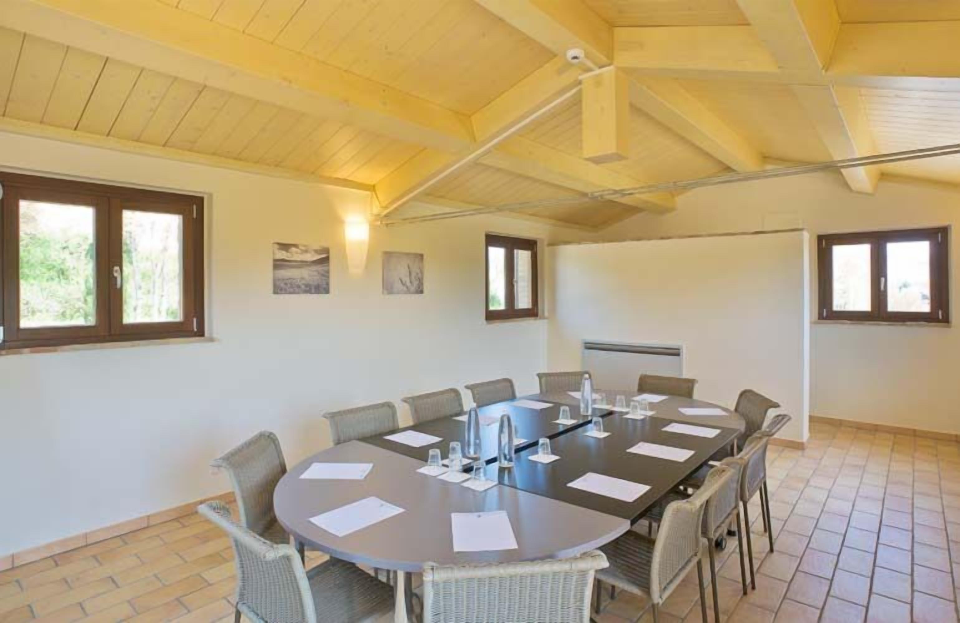 A conference room with a large round table, chairs, and a ceiling fan.