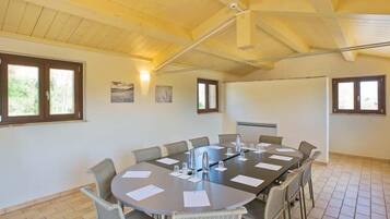 A conference room with a large round table, chairs, and a ceiling fan.