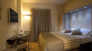 Una habitación de hotel con una cama, un escritorio con una silla, un televisor y cortinas.