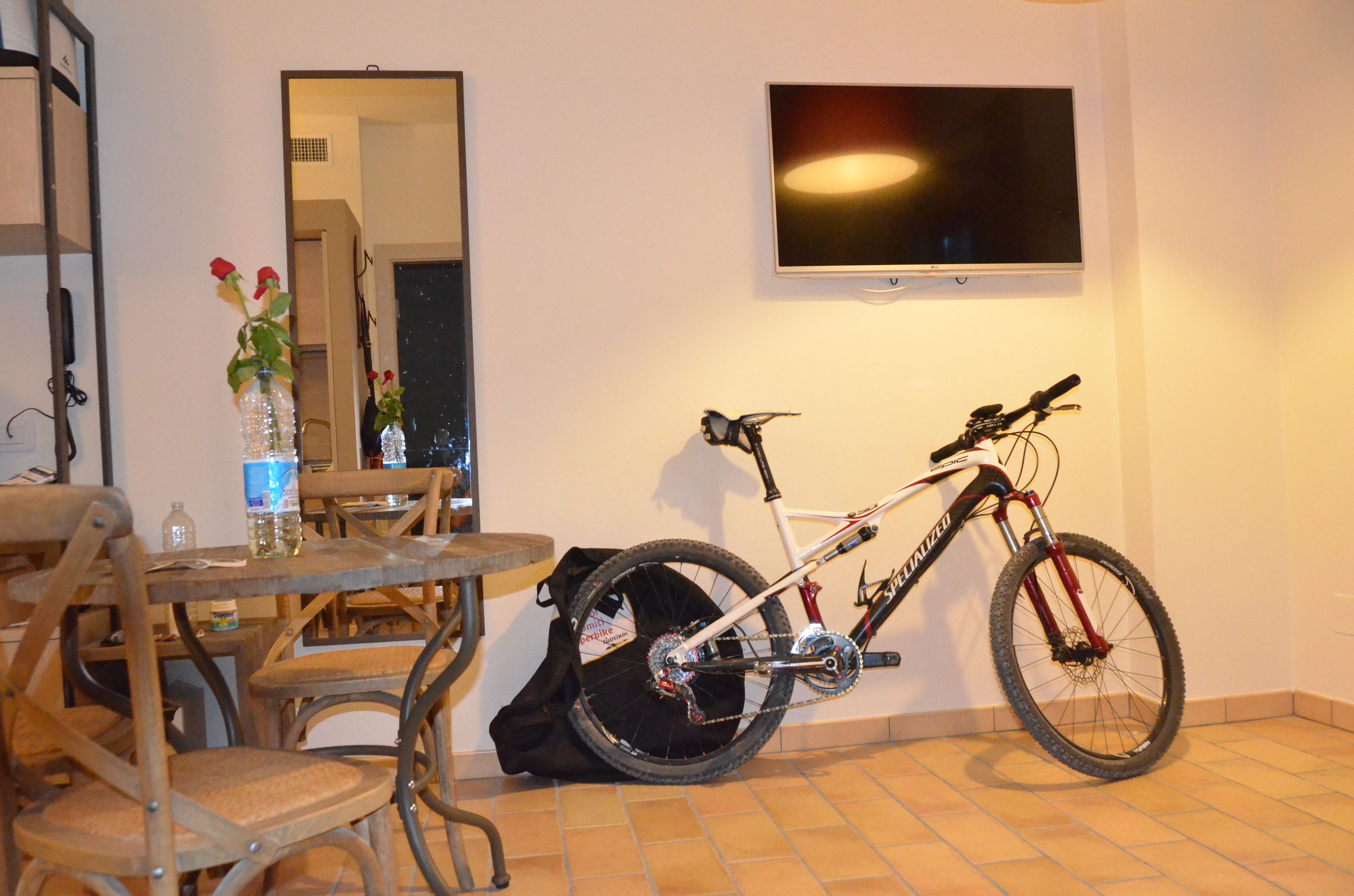 Un comedor con una mesa, sillas, un florero con flores y una bicicleta apoyada en la pared.