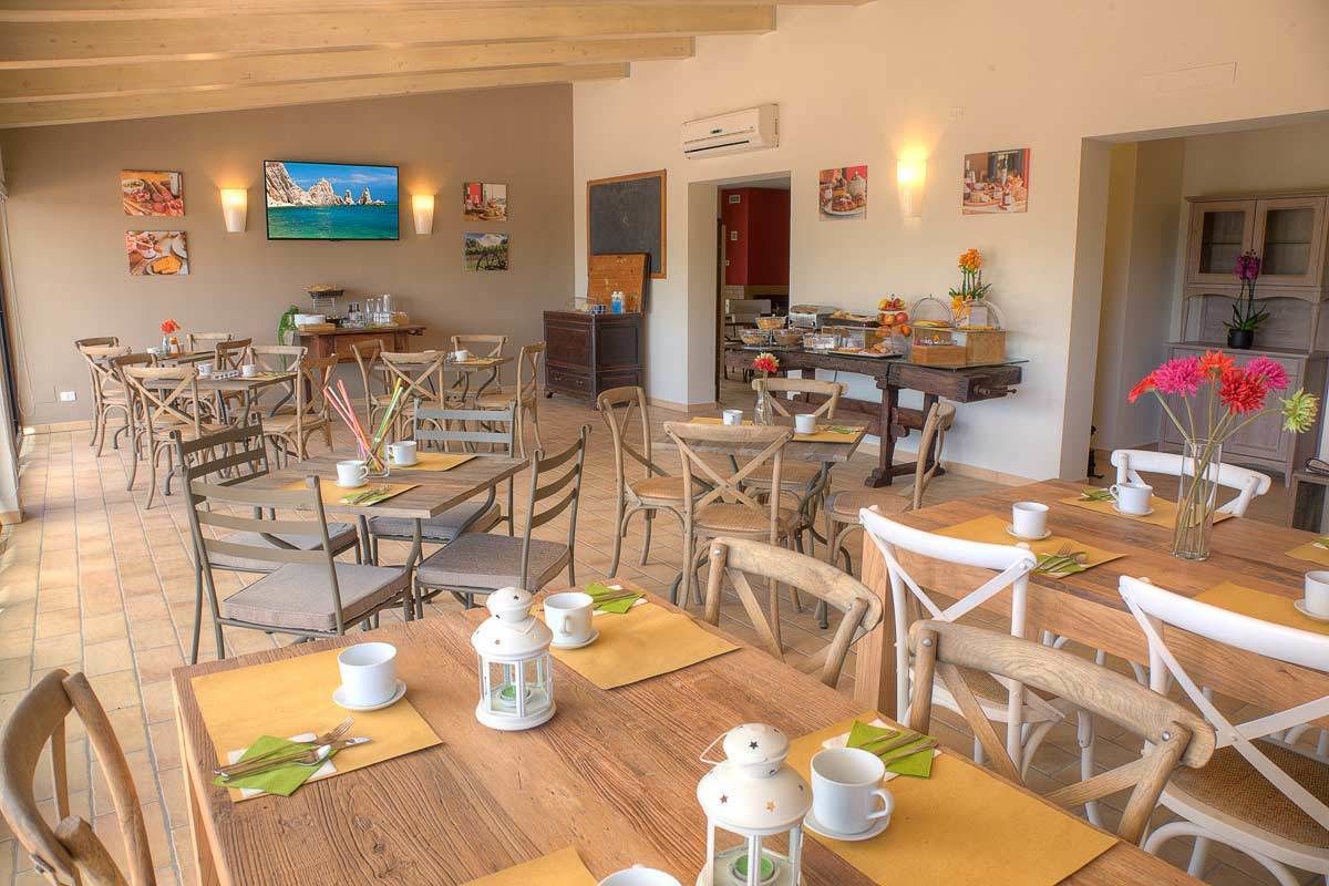 Un comedor con mesas y sillas de madera, un televisor montado en la pared y obras de arte decorando las paredes.