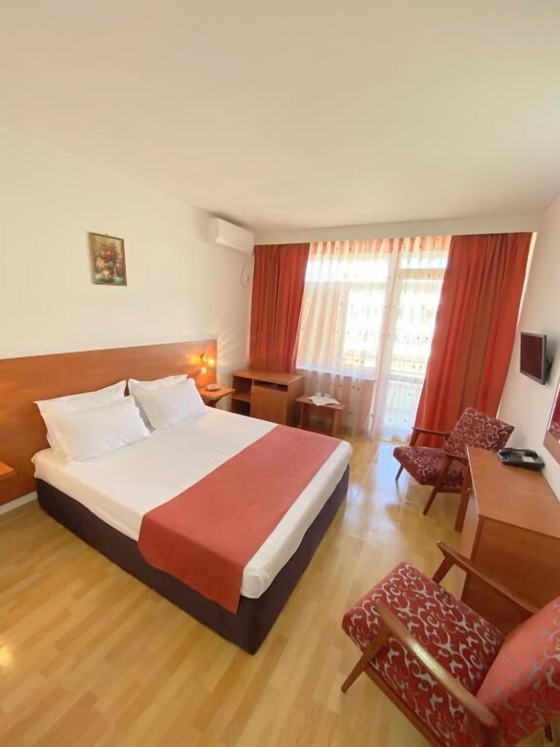 Une chambre d’hôtel avec un grand lit, un bureau, une chaise et un téléviseur.