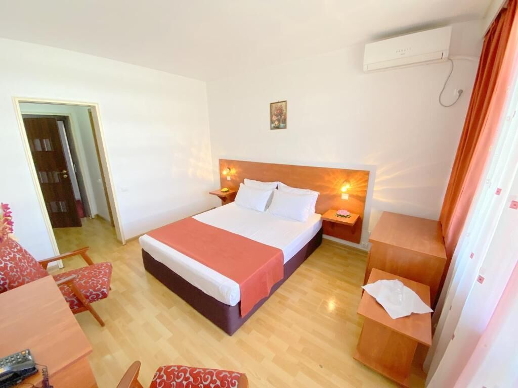 Quarto de hotel com cama, mesas de cabeceira, escrivaninha e cadeira.