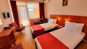 A hotel room with two beds, a desk, a chair, and a TV. - Tomis Hotel Neptun  (Neptun)
