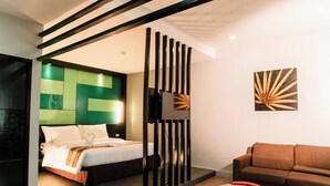 A modern hotel room with a bed, a sofa, a coffee table, and a decorative wall piece. - Sun City Suites (General Santos)