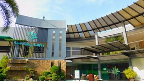 A hotel entrance with a sign reading "SunCity Suites," a covered outdoor area, and a stone facade. - Sun City Suites (General Santos)