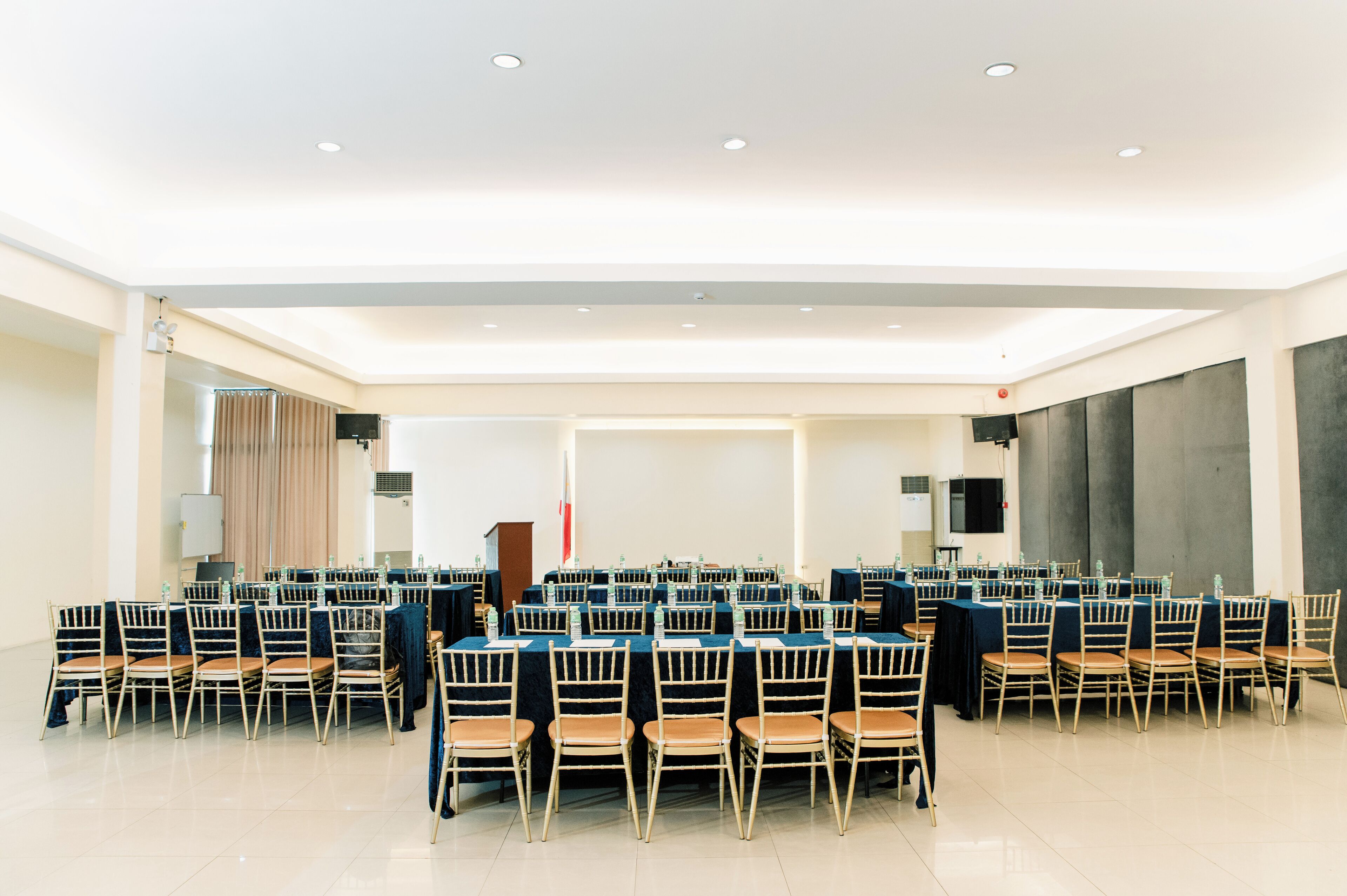 A conference room with rows of tables and chairs, equipped with water bottles and nameplates.
