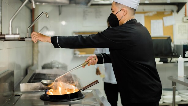 A chef cooking with a portable stove in a commercial kitchen. - Sun City Suites (General Santos)
