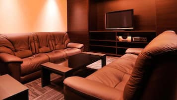 Un salon moderne avec des canapés en cuir, une table basse et un téléviseur à écran plat posé sur une étagère en bois.