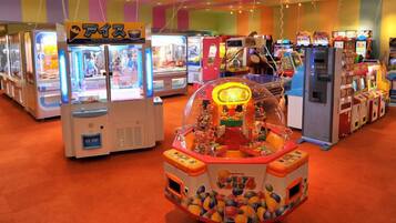 Eine Indoor-Spielhalle mit verschiedenen Spielautomaten und einem zentralen Spielplatz mit bunten Bällen.
