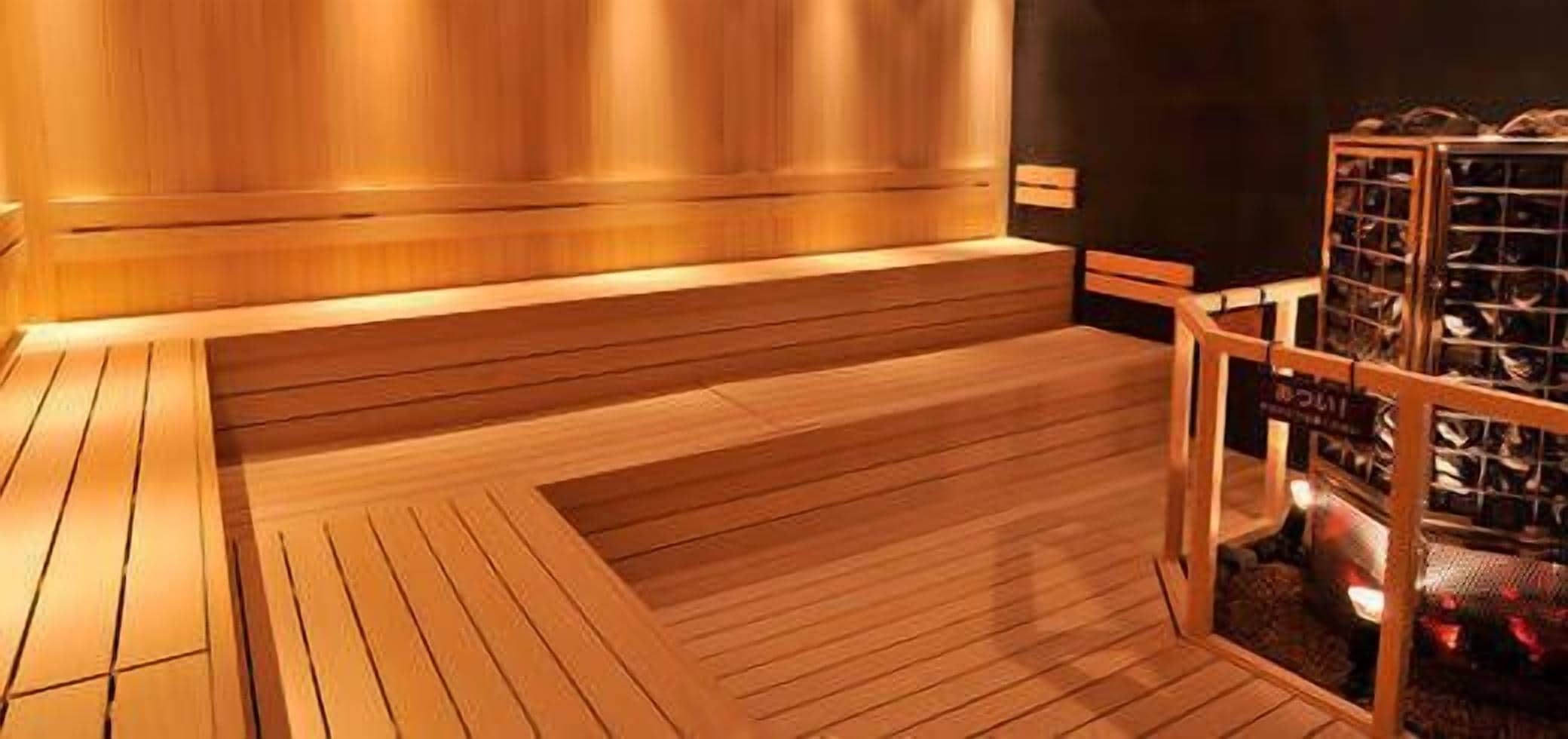 A wooden sauna with benches and a glass-walled sauna room.