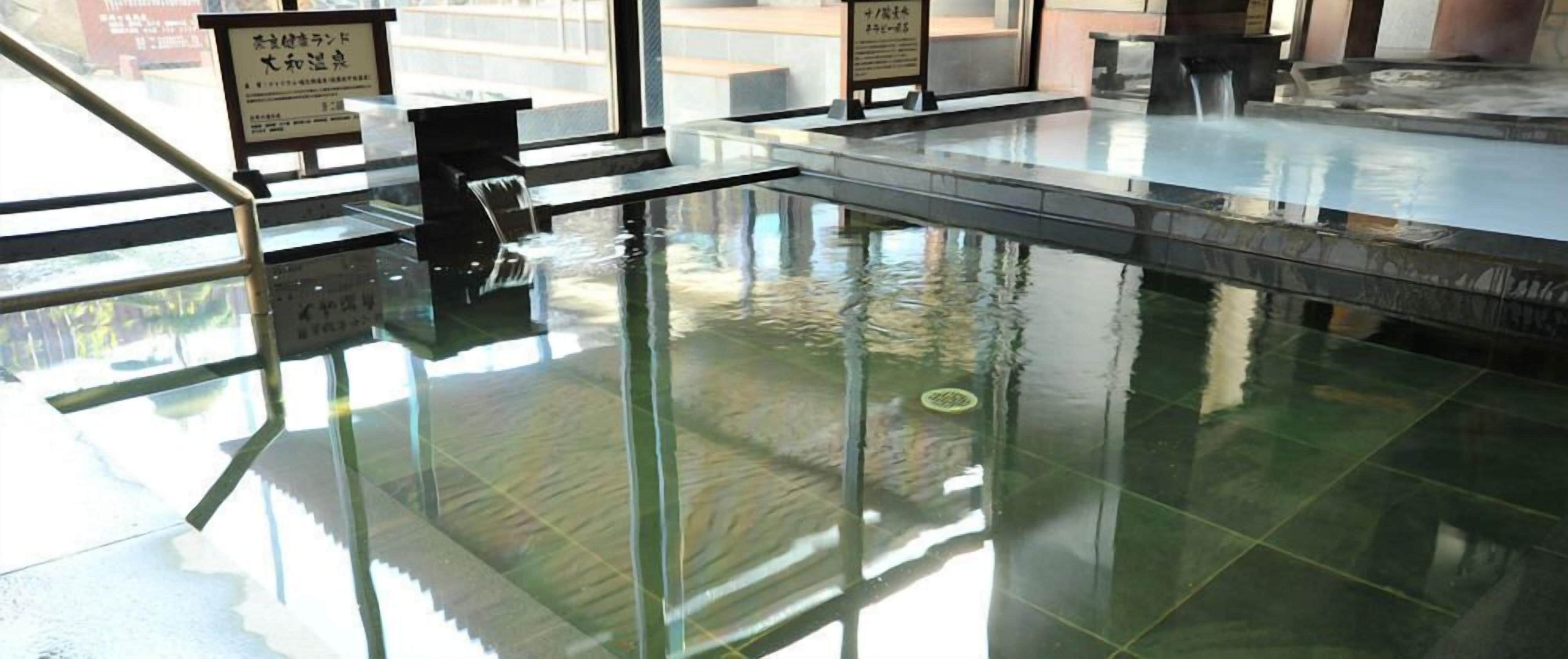 A modern indoor pool area with clear glass flooring and a central water feature.
