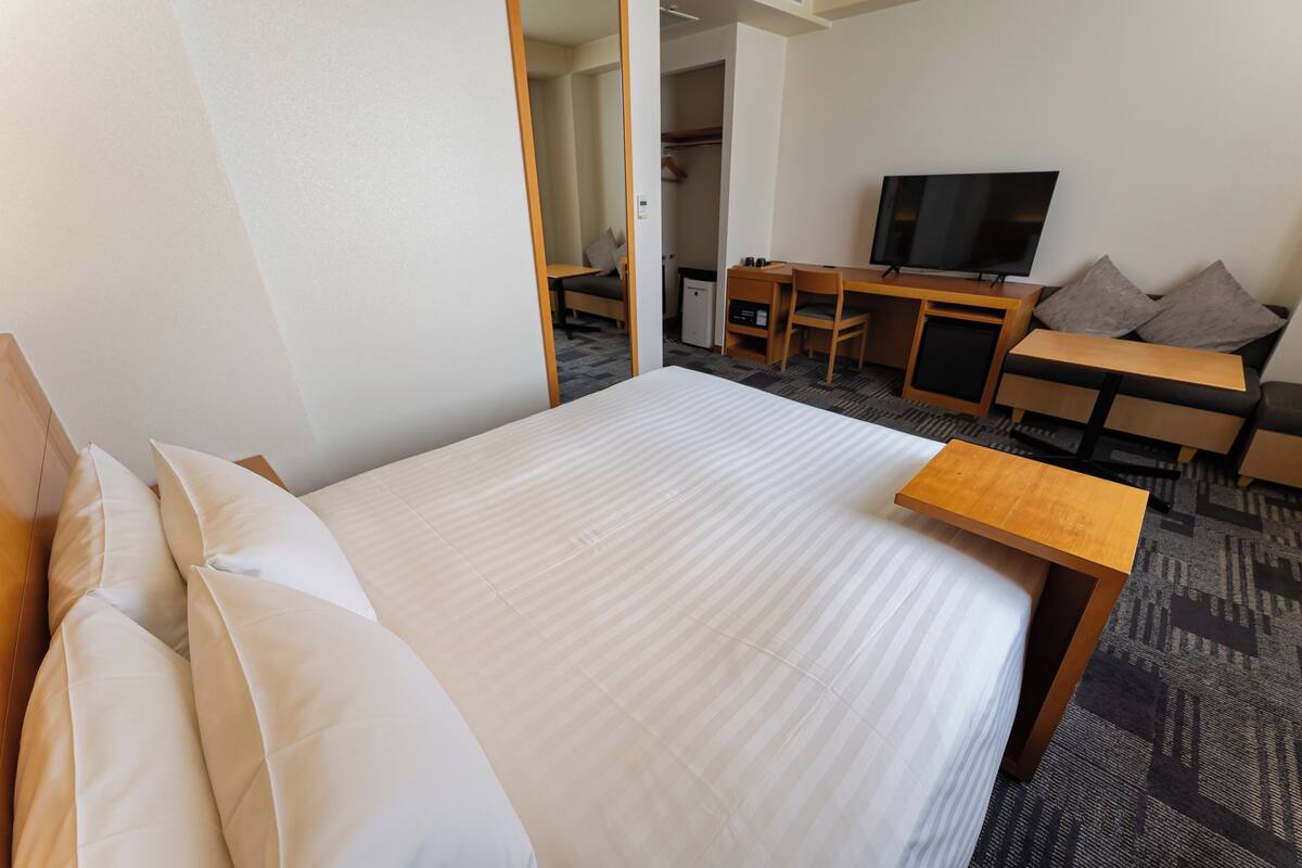 Ein Hotelzimmer mit Bett, Schreibtisch, Fernseher und Sitzecke.