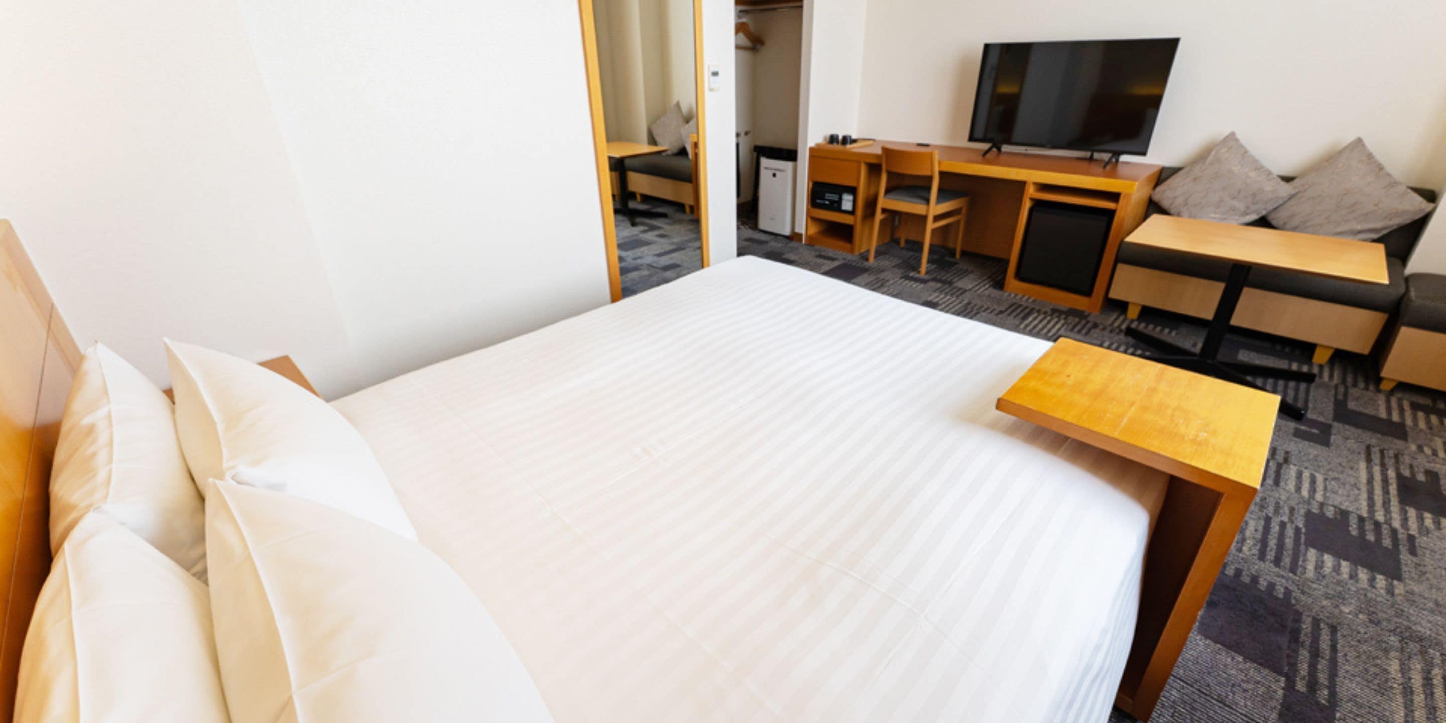 Una habitación de hotel con una cama, un escritorio, un televisor y un sofá.