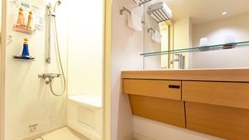 A bathroom with a shower, a glass shelf with toiletries, and a wooden vanity with a mirror.