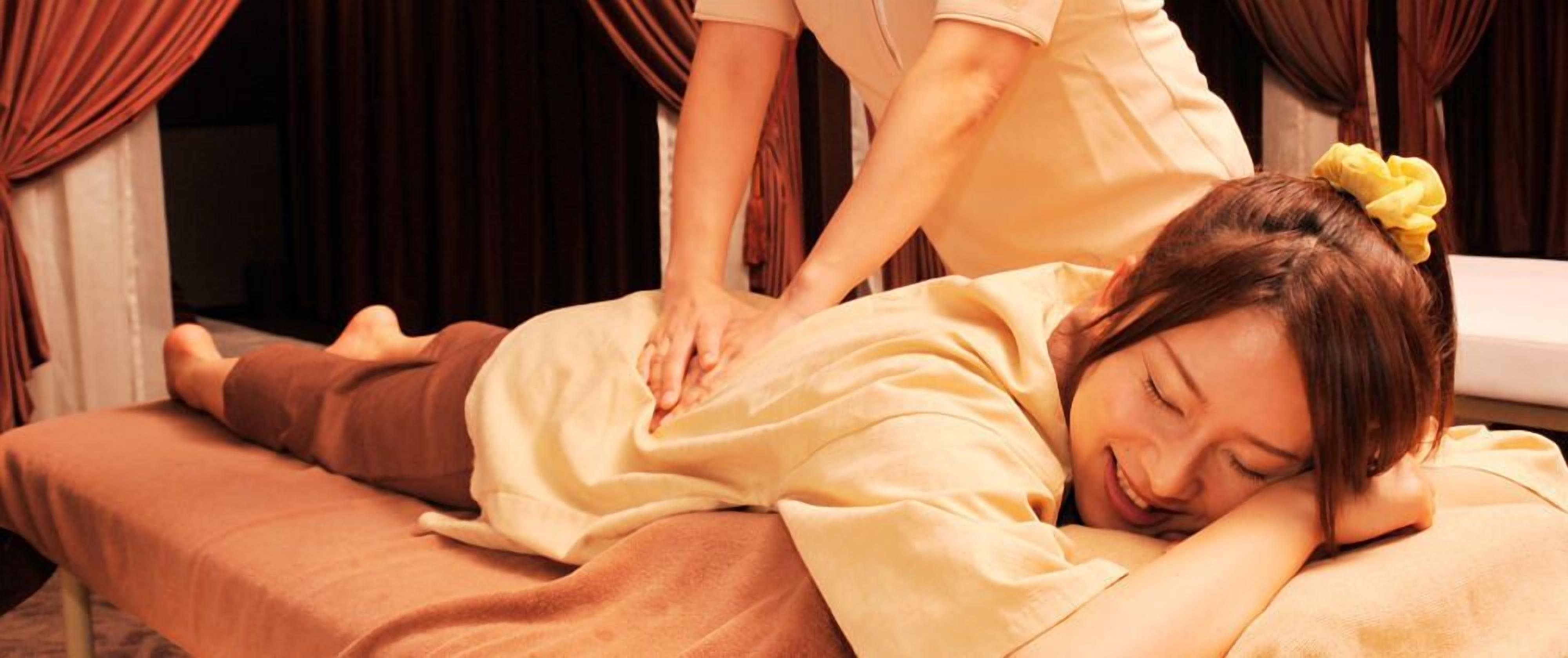 Une personne allongée sur une table de massage, recevant un massage du dos.