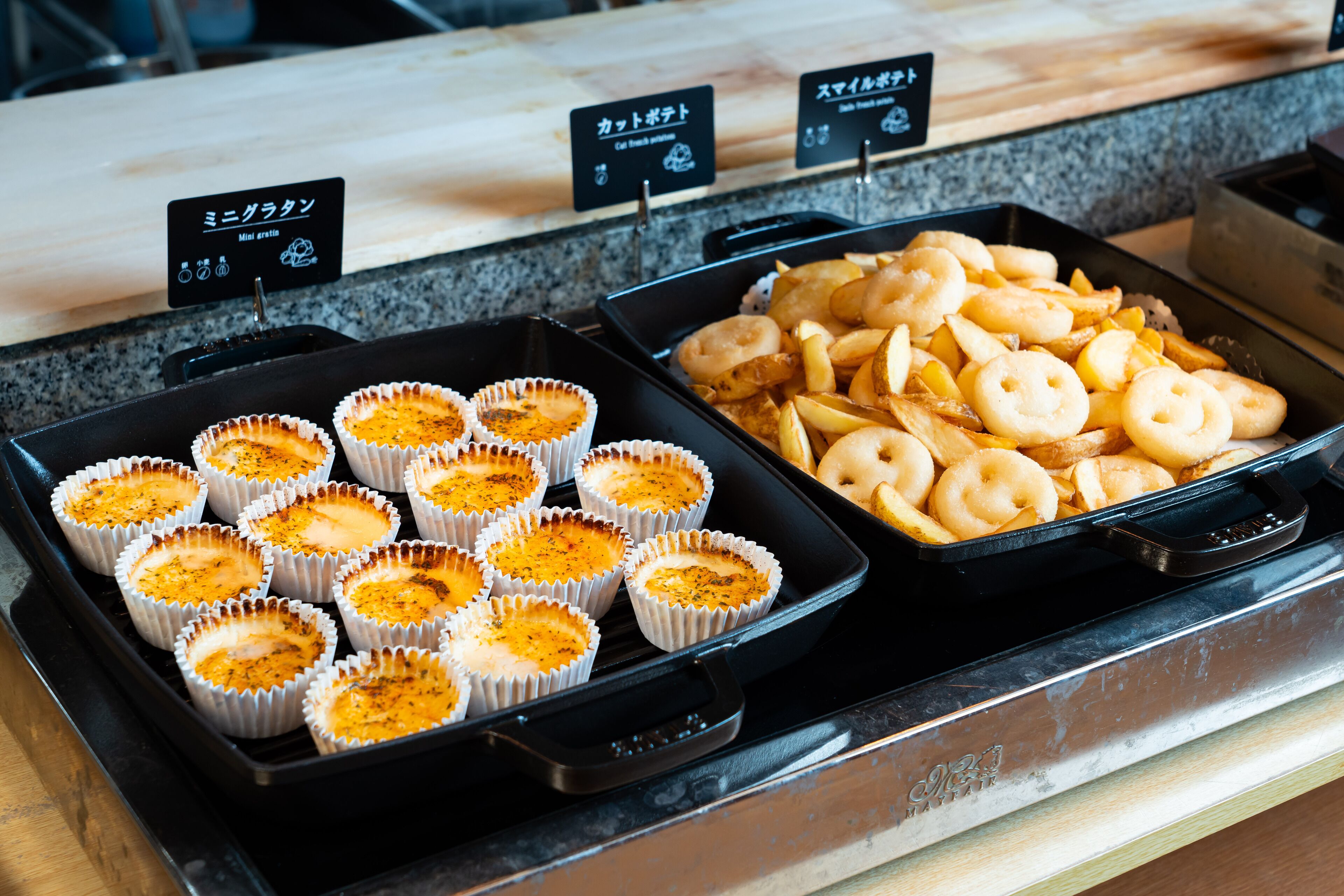 A buffet with various food items, including cupcakes and fried snacks.