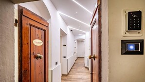 A hallway with wooden doors, a security keypad, and a light switch on the wall. - B&B Lorenzo de' Medici (Florence)