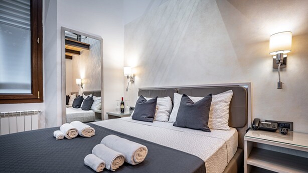 A modern hotel room with a large bed, two bedside tables, a mirror, and wall-mounted lights. - B&B Lorenzo de' Medici (Florence)