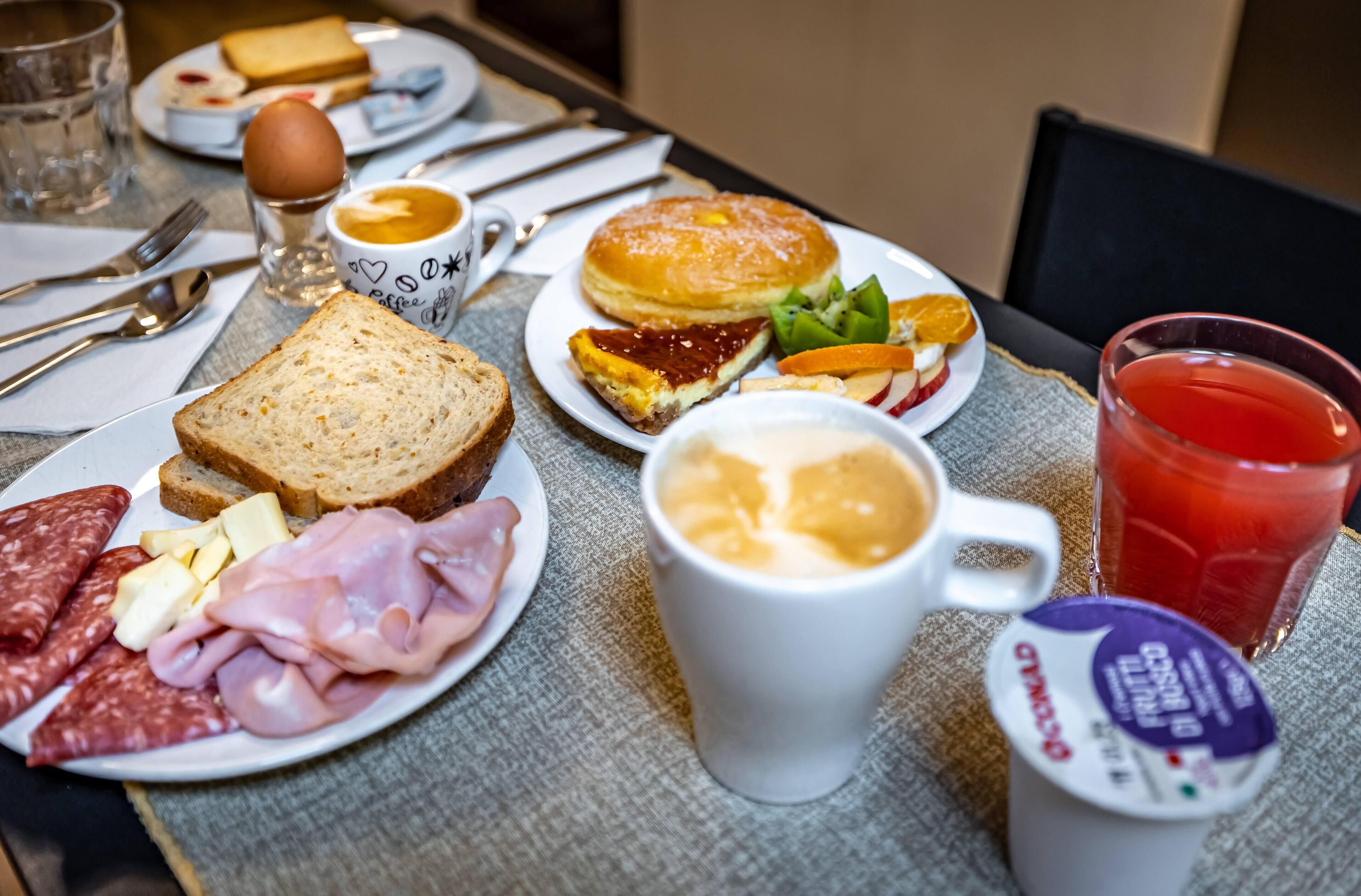 Ein Frühstückstisch mit Toast, Eiern, Schinken, Käse und verschiedenen Aufstrichen.