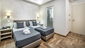 A hotel room with two beds, a desk, a nightstand, and a bathroom with a glass door. - B&B Lorenzo de' Medici (Florence)