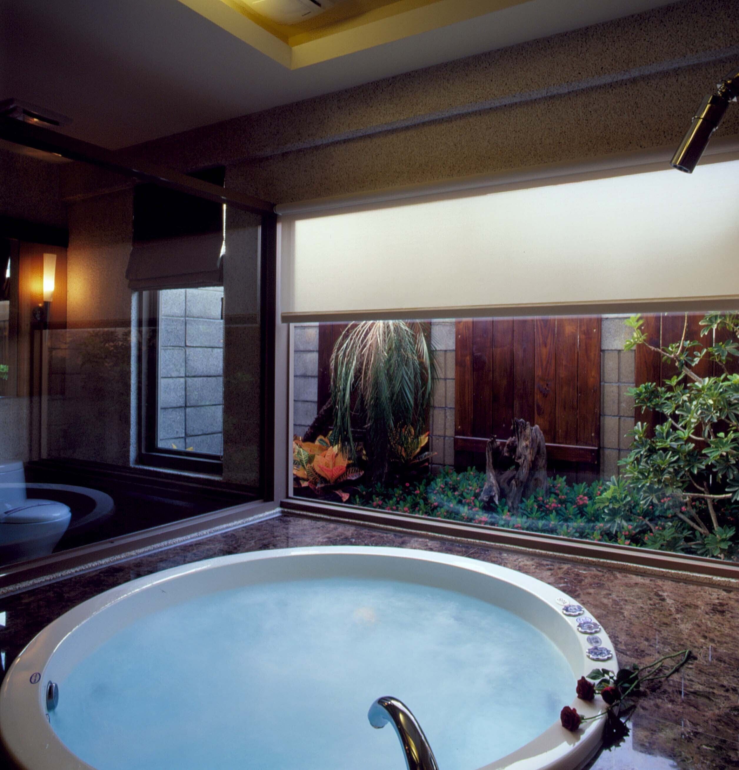 A large bathtub with a view of a wooden deck and plants.