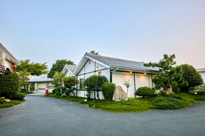 A modern two-story house with a tiled roof, surrounded by well-maintained greenery and a driveway. - Gold Motel (Puxin)