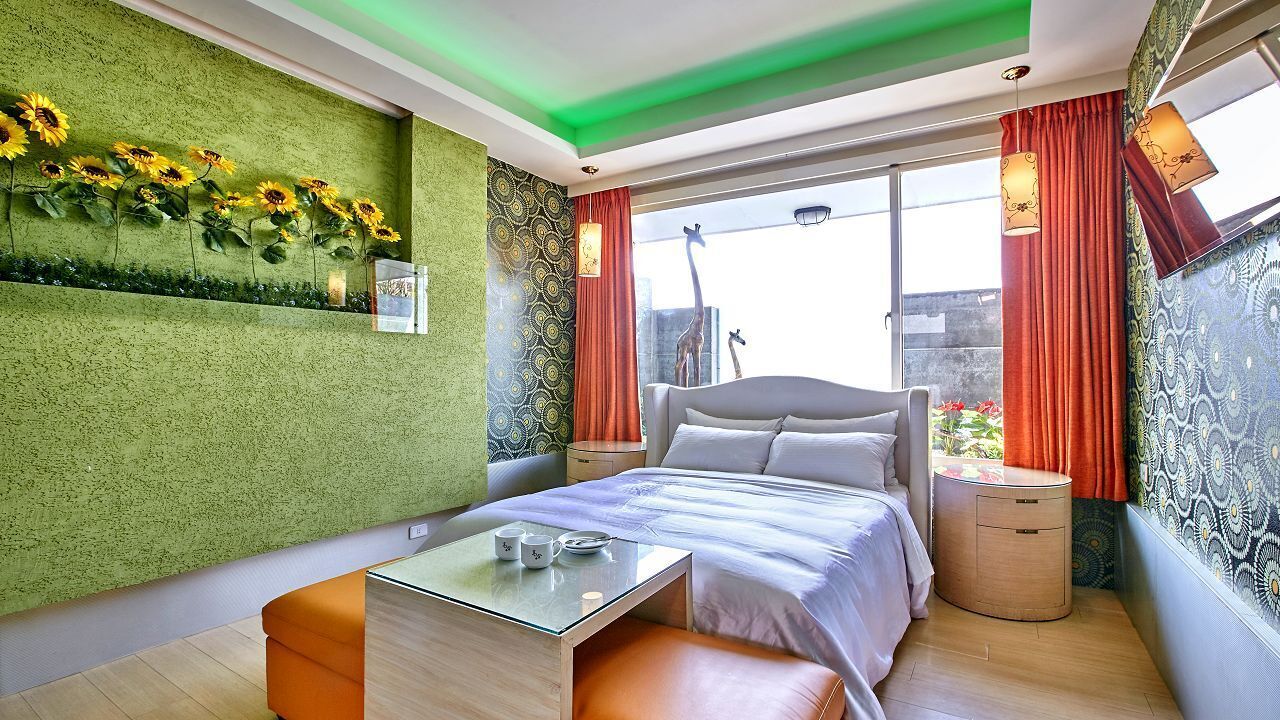 Un dormitorio moderno con cama, una mesita de vidrio y una pared verde con textura.