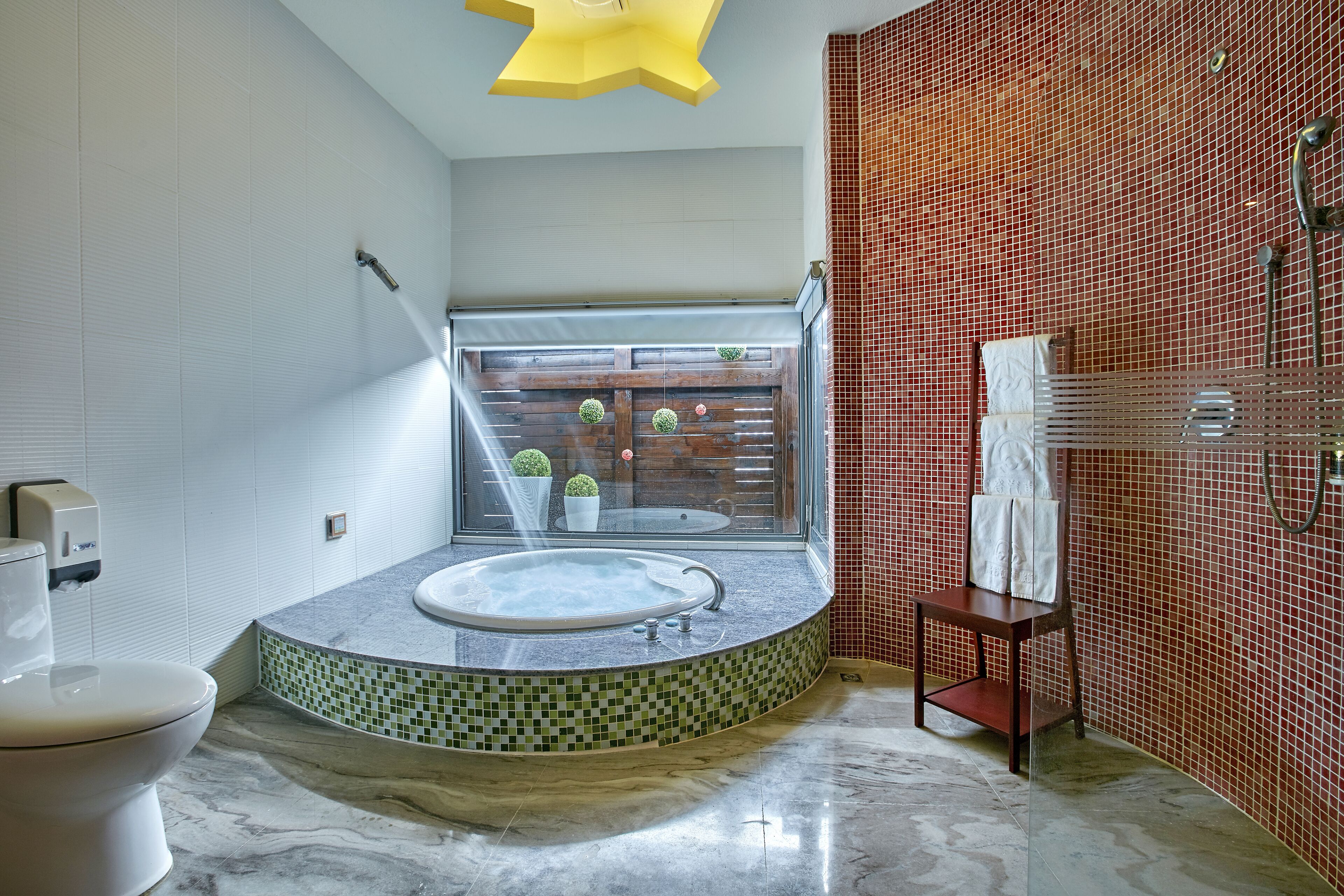 Un baño moderno con una bañera independiente, un inodoro y una ventana con vista a un balcón.