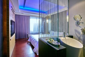 A modern hotel room with a large bed, a glass-enclosed bathroom, and a view of the outdoors. - Gold Motel (Puxin)
