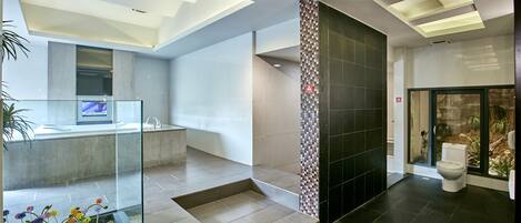 Un baño moderno con cabina de ducha de vidrio, inodoro a la vista y zona de lavamanos.
