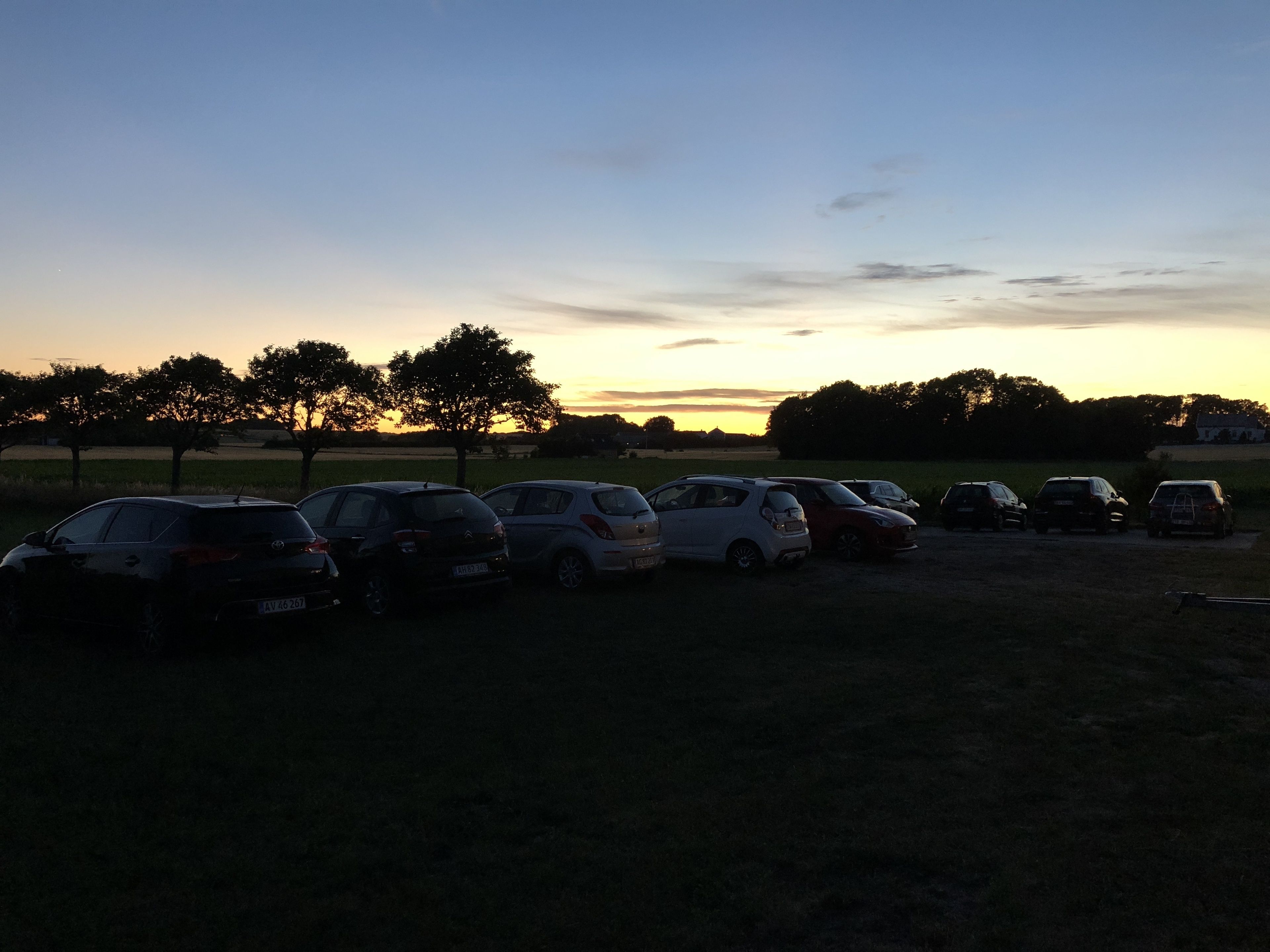 Ein Parkplatz mit mehreren Autos bei Sonnenuntergang.