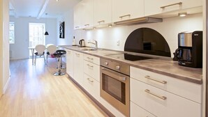 A modern kitchen with white cabinets, stainless steel appliances, and a large island. - Myregaard B&B & Apartments (Nexø)