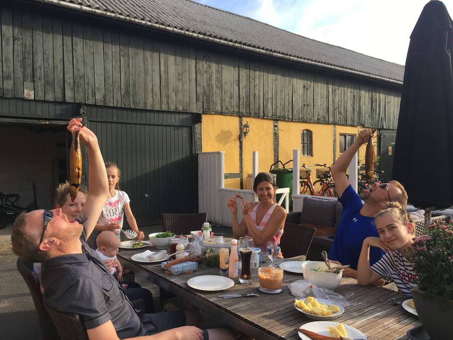 A group of people dining outdoors at a wooden table with various dishes and drinks.
