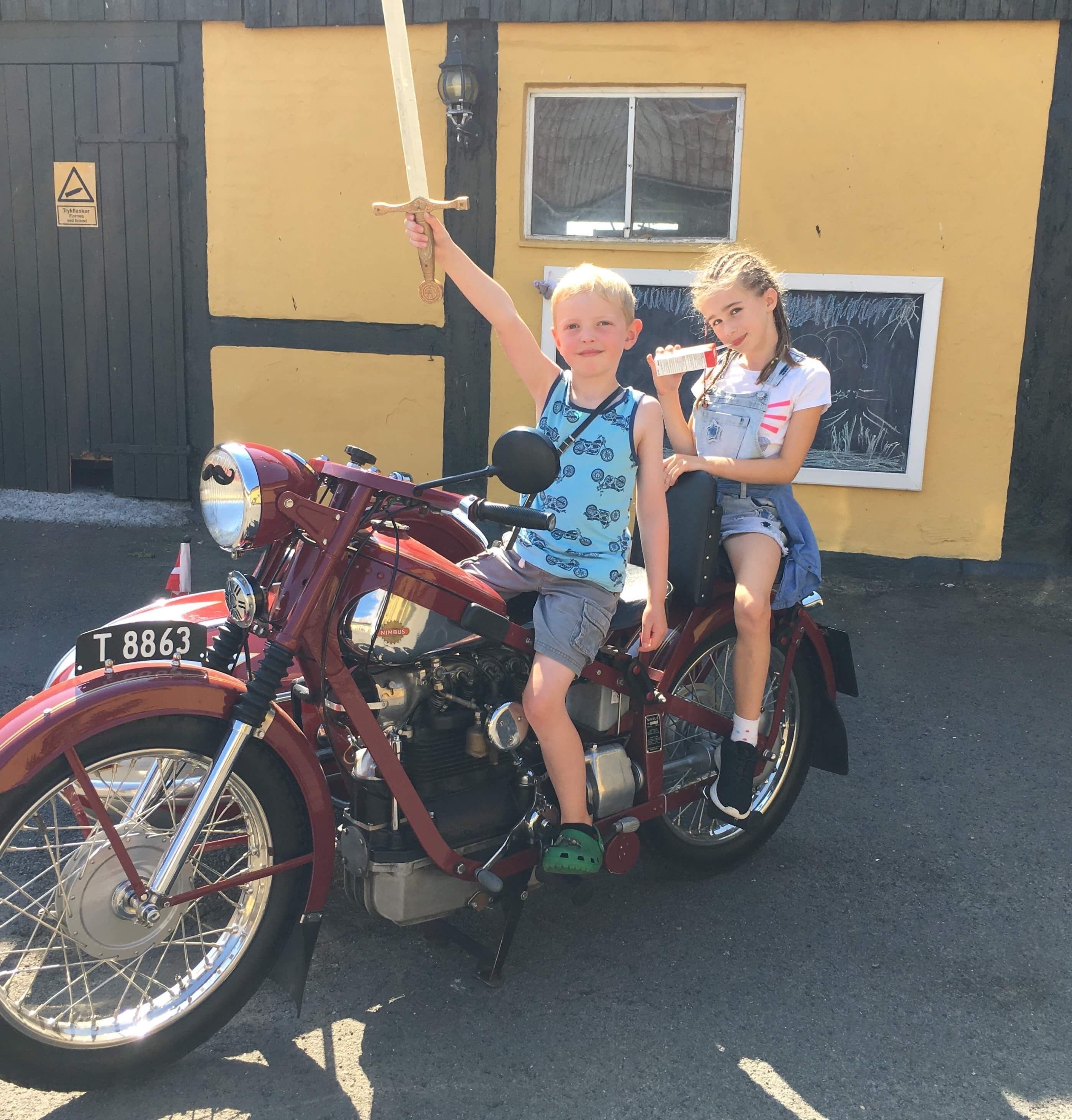 Two children on a vintage motorcycle with a license plate T 8863.