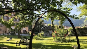 Un jardín tranquilo con un banco, un estanque pequeño y una construcción rústica al fondo.