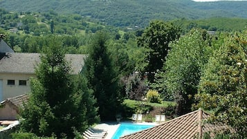 A residential area with a swimming pool surrounded by lush greenery and a view of distant hills.