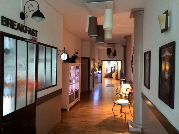 A hallway with a breakfast sign, a clock, and a chair with a lamp. - Logis Hôtel Restaurant Le Castel Fleuri (Saint-Jean-en-Royans)