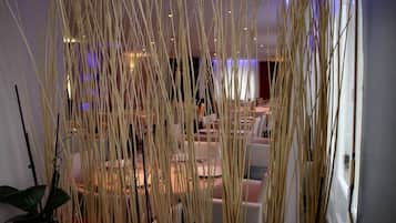Un intérieur moderne, agrémenté d’éléments décoratifs hauts et fins, d’un espace salon avec des tables et des chaises, et d’une plante en pot.