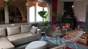 Una sala de estar moderna con un sofá, sillas, una chimenea y un ventanal grande.